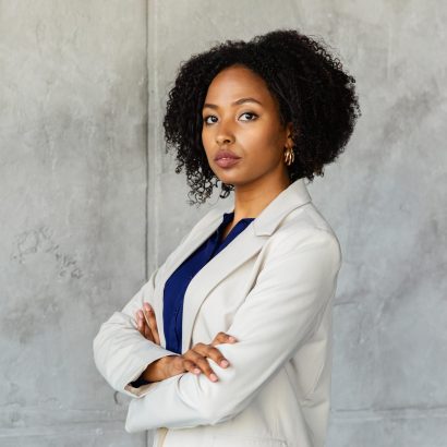 Carrer, professional lifestyle, success concept. Successful confident pretty young african american woman in formal suit manager posing with hands crossed on chest over marble wall, copy space